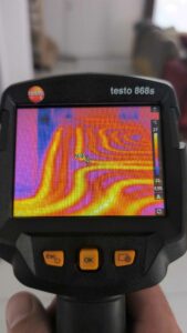 Expert chauffagiste utilisant une caméra thermique pour une expertise de fuite sur un plancher chauffant.